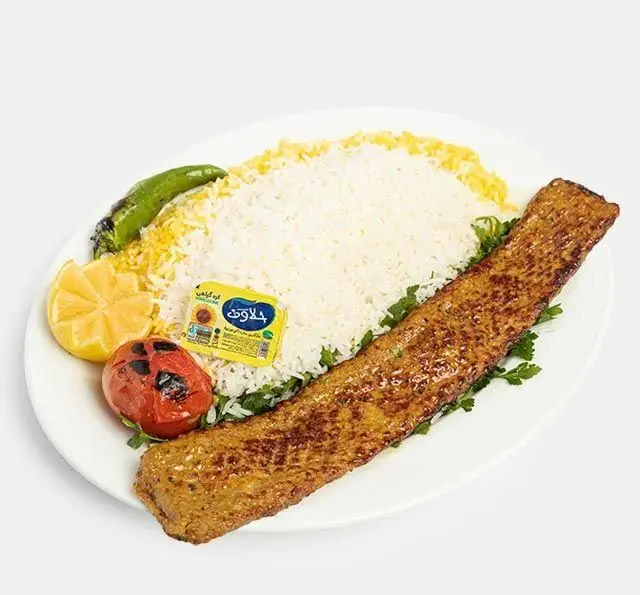 تصویری از چلو کباب کوبیده لذیذ رستوران سنتی آفاق، یک غذای سنتی ایرانی با برنج زعفرانی، گوجه کبابی، فلفل و کره.