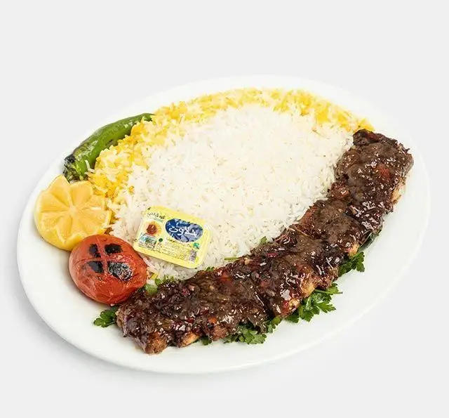 چلو کباب دنده رستوران سنتی آفاق؛ شامل دنده گوسفندی طعم دار شده، برنج زعفرانی، گوجه کبابی، لیمو و کره.