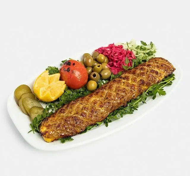 ماهی کباب سنتی آفاق، غذای اصیل ایرانی با رنگ طلایی و مخلفات تازه شامل لیمو، زیتون، گوجه کبابی و ترشی.