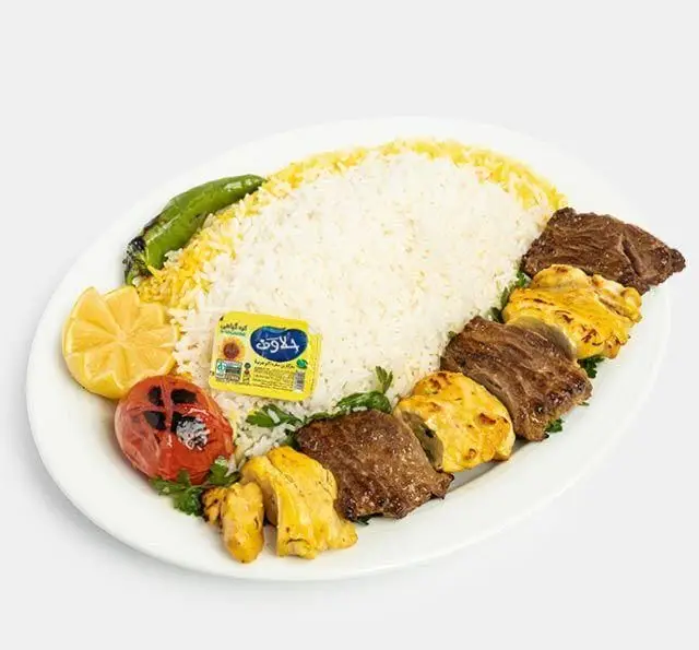 چلوکباب بختیاری اصیل و دلپذیر رستوران سنتی آفاق، شامل تکه‌های کباب گوشت و مرغ، با برنج زعفرانی ایرانی، گوجه و فلفل کبابی، و کره.