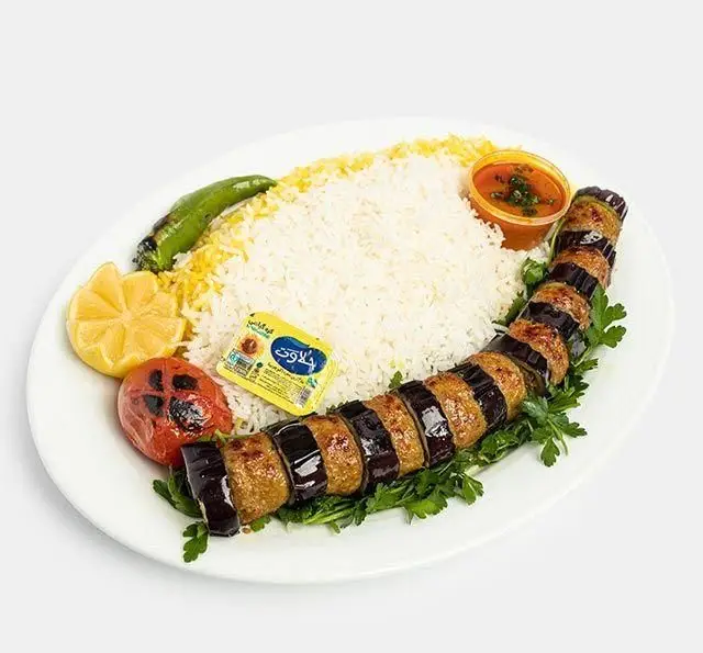 چلو کباب بادمجان کوبیده رستوران سنتی آفاق؛ غذای اصیل ایرانی شامل کباب پیچیده در بادمجان، برنج، گوجه، فلفل، لیمو و سس مخصوص.
