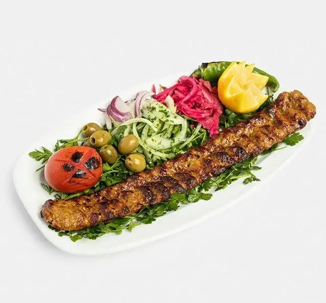 تصویر کباب کوبیده اصیل و خوش طعم رستوران سنتی آفاق، تزئین شده با گوجه کبابی، پیاز، زیتون، فلفل و سبزی تازه.