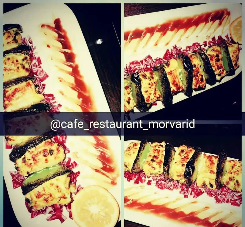 غذای خوشمزه رستوران مروارید شامل بادمجان‌های شکم‌پر با پنیر و سیب‌زمینی سرخ کرده با سس قرمز و لیمو ترش برای تزئین.