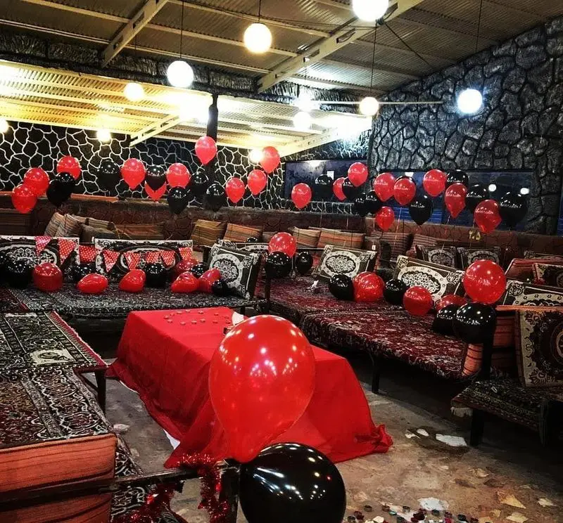دکوراسیون شیک و جذاب رستوران مروارید برای جشن‌های خاص با بادکنک‌های قرمز و مشکی در فضای سنتی و دلنشین.