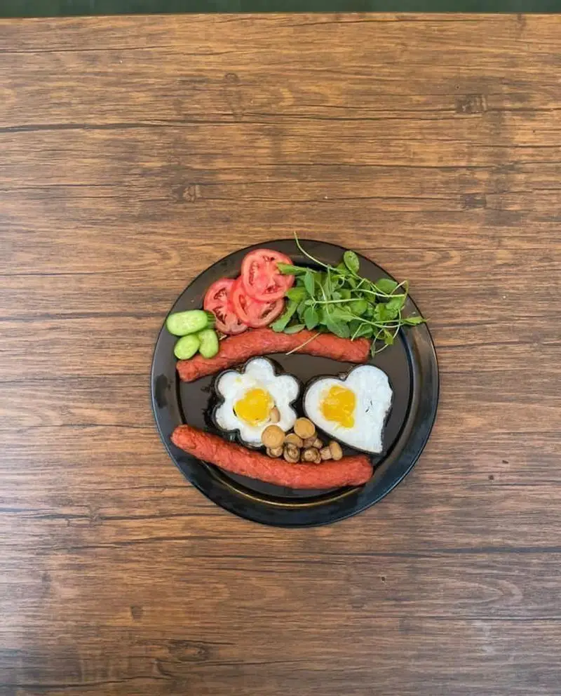 صبحانه متفاوت و جذاب کافه رستوران حیات نو: بشقاب خندان با سوسیس، تخم مرغ‌های قلبی و گلی، قارچ، گوجه و سبزیجات.