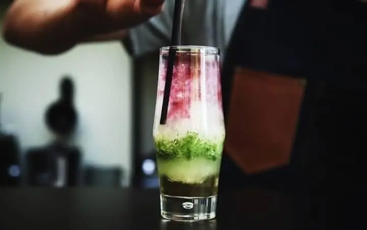 نمایی از آماده سازی نوشیدنی خنک و میوه‌ای لایه ای توسط باریستا در کافه رستوران حیات نو، انتخابی ایده‌آل برای تابستان.