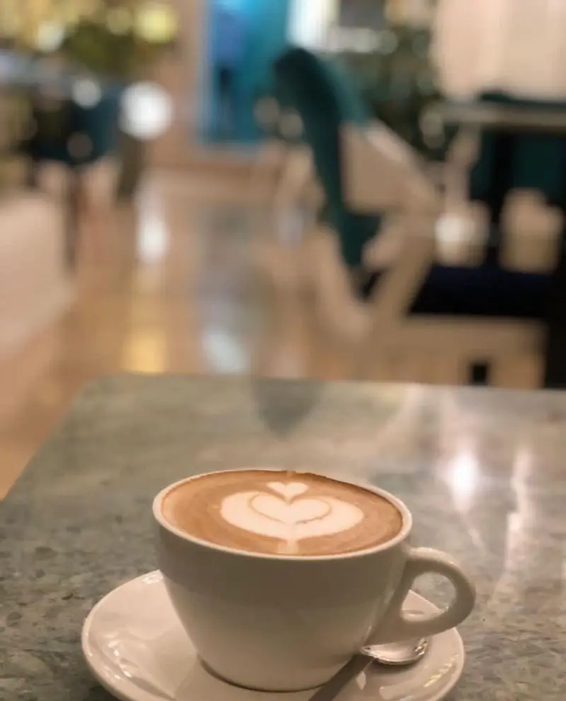 نوشیدنی گرم لاته با طرح هنری قلب روی میز مرمرین کافه رستوران حیات نو؛ فضایی ایده‌آل برای دورهمی‌ها و لحظاتی دلنشین در کافه.