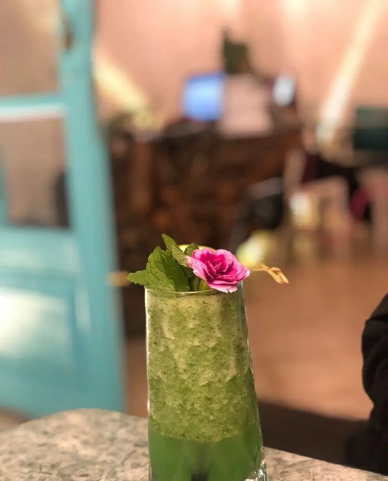 نوشیدنی اسموتی سبز و خنک با برگ نعناع و گل صورتی، مناسب روزهای گرم در کافه رستوران حیات نو، تجربه‌ای دلنشین و تازه.