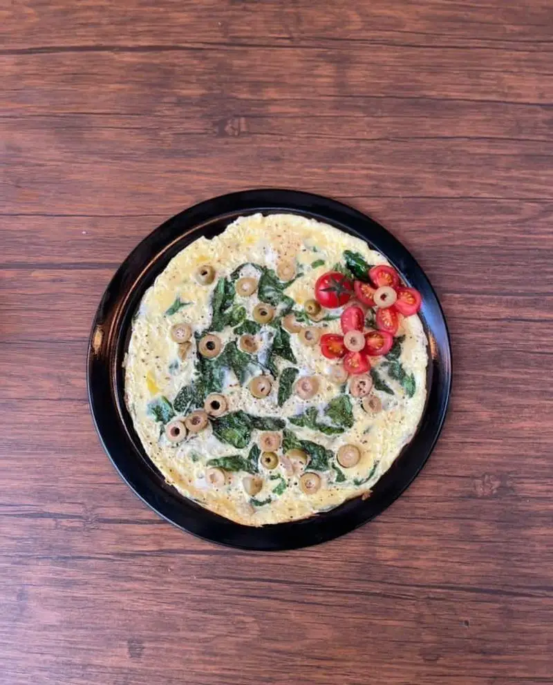 املت شیک و لذیذ اسفناج و زیتون، تزیین شده با گل‌های گوجه گیلاسی در کافه رستوران حیات نو، انتخابی سالم برای صبحانه شما.