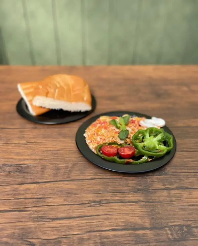 صبحانه دلچسب کافه رستوران حیات نو: املت خوش‌رنگ و نان تازه سرو شده روی میز چوبی با تزئین گوجه و فلفل سبز.