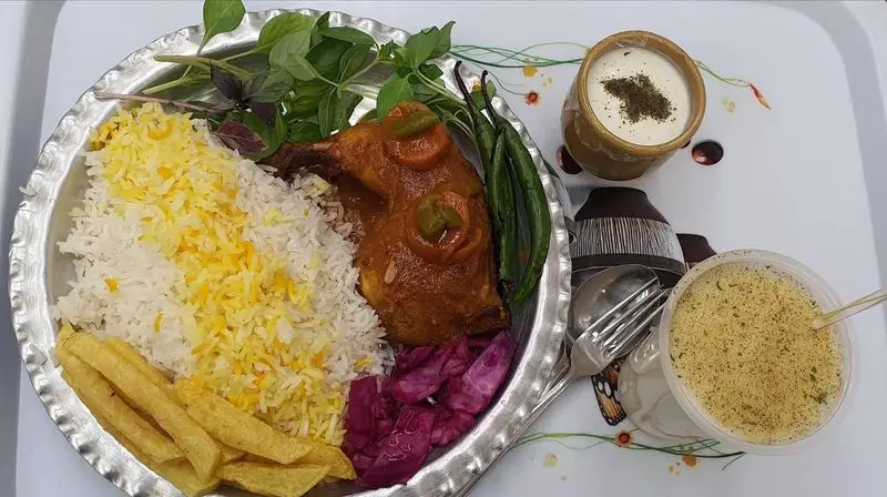 یک پرس چلو مرغ مجلسی از رستوران زیتون با برنج ایرانی، سیب زمینی، ترشی کلم بنفش و سبزی تازه. همراه سوپ و دوغ سنتی.