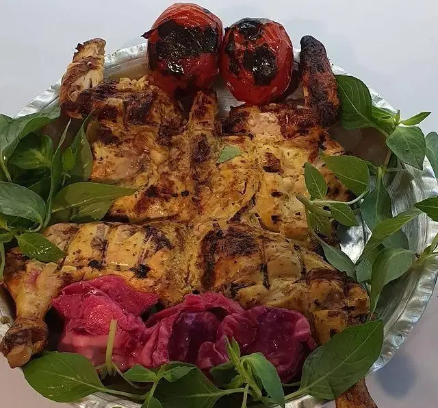 جوجه کبابی پرسی ویژه رستوران زیتون همراه با گوجه کبابی، سبزی ریحان و ترشی کلم قرمز. غذای سنتی ایرانی.