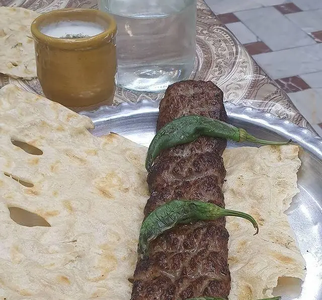 یک سیخ کباب کوبیده آبدار به همراه نان تازه، فلفل سبز کبابی و دوغ محلی رستوران زیتون؛ غذایی اصیل و محبوب ایرانی.