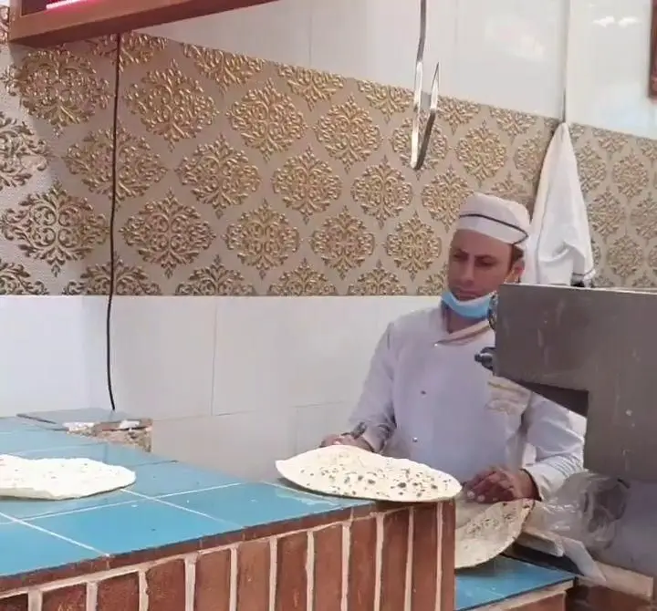آشپز ماهر رستوران زیتون در حال آماده‌سازی نان لواش داغ و تازه، نان سنتی و خوشمزه با رعایت کامل بهداشت