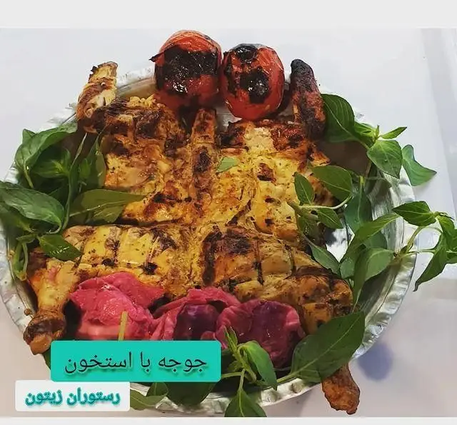 سینی بزرگ جوجه با استخوان کبابی خوشمزه رستوران زیتون، همراه با گوجه فرنگی‌های کبابی و برگ‌های تازه ریحان؛ یک غذای اصیل ایرانی.