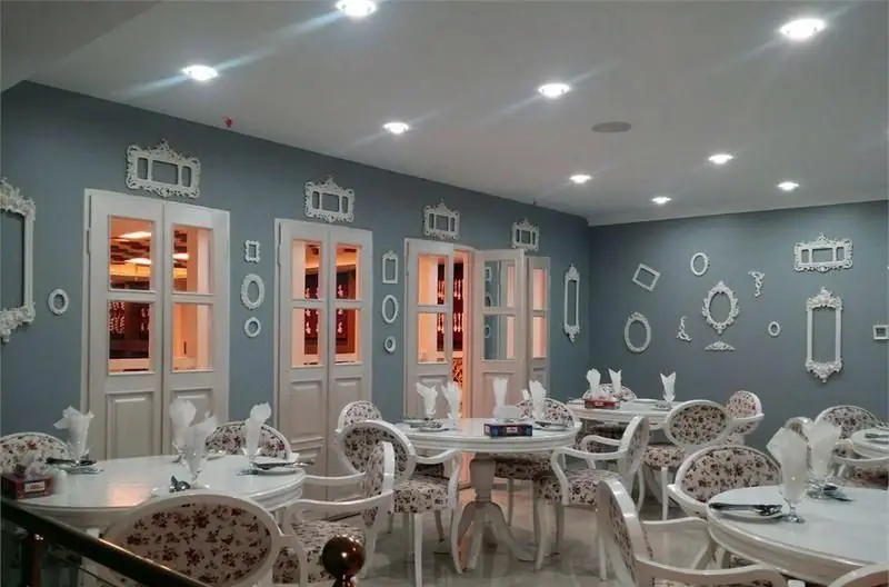 دکوراسیون داخلی شیک و مدرن رستوران ماهی سفید: دیوارهای آبی روشن با قاب‌های تزئینی سفید و میز و صندلی‌های راحت برای تجربه‌ای دلپذیر.