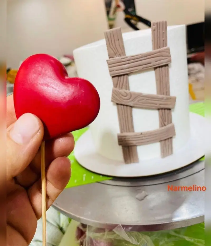 قنادی نارملینو: کیک سفید با تزئین نردبان چوبی و قلب قرمز فانتزی، بهترین گزینه برای جشن تولد و لحظات عاشقانه.