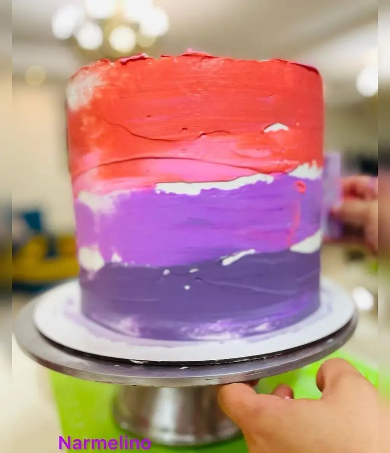کیک مدرن و خاص قنادی نارملینو با طرح پالت رنگی قرمز، صورتی و بنفش. این دسر خوشمزه برای جشن‌های تولد و مراسم شماست.