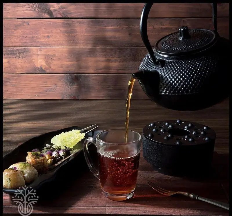 سرو چای داغ از قوری چدنی به همراه شیرینی‌های سنتی و نبات در کافه رستوران لوکال ولنجک، تجربه‌ای دلنشین.