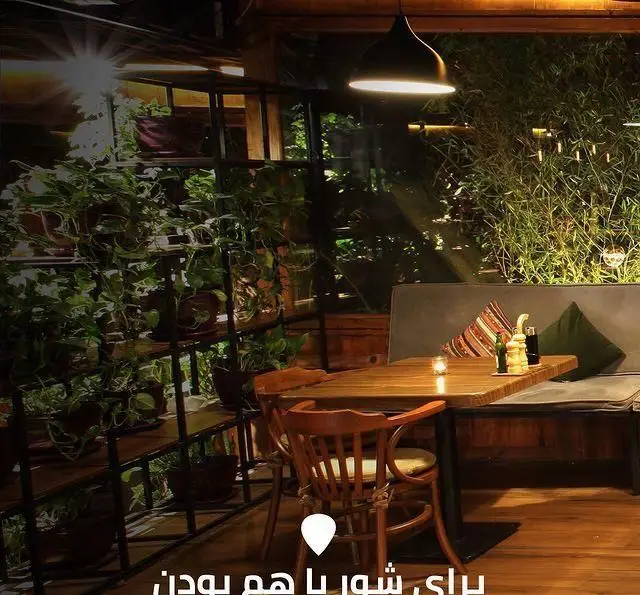 فضای دنج و دلنشین کافه رستوران لوکال ولنجک با دکوراسیون سرسبز گیاهی، میزهای چوبی شیک و نورپردازی گرم و آرامش‌بخش برای تجربه ای خاص.