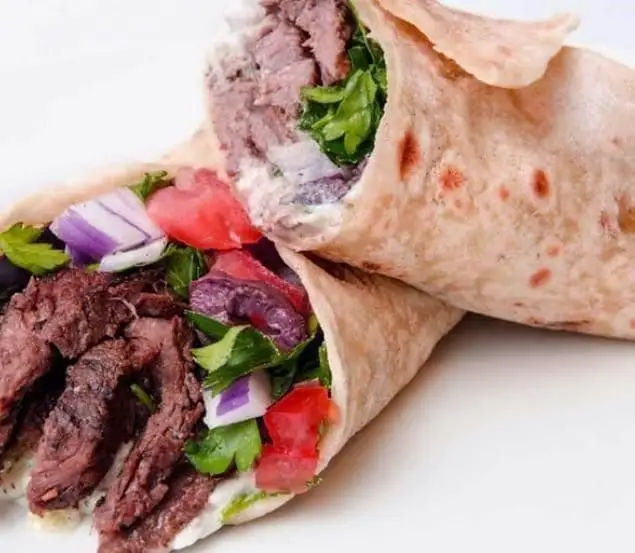 رول دونر کباب گوشت لذیذ از رستوران دونر افندی، با سبزیجات تازه، پیاز قرمز، گوجه فرنگی و سس مخصوص. یک غذای ترکی خوشمزه.