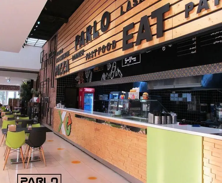 فضای داخلی فست فود پارلو با دکوراسیون چوبی و آجری، شامل بخش سفارش و میز سرو پیتزا، برگر و فست فودهای متنوع. محیطی مدرن و دلنشین.
