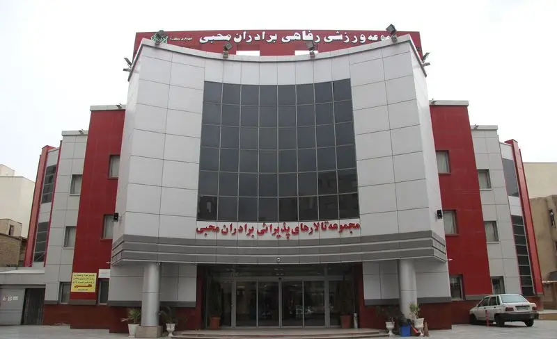 نمای بیرونی مجتمع ورزشی و استخر برادران محبی با طراحی مدرن، پانل‌های سفید و قرمز و پنجره‌های بزرگ سیاه در مرکز.