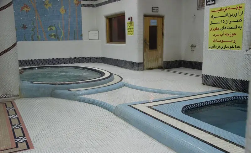 فضای داخلی تمیز و مدرن استخر مجموعه ورزشی برادران محبی با جکوزی آب گرم، حوضچه آب سرد و امکانات سونا، طراحی زیبا با کاشی‌های سفید و آبی.