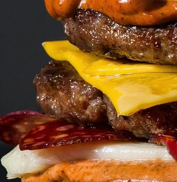 برگر ویژه 1358 بلوار اباذر: یک برگر بزرگ با دو لایه گوشت آبدار، پنیر چدار آب شده، پپرونی و سس مخصوص روی نان نارنجی.