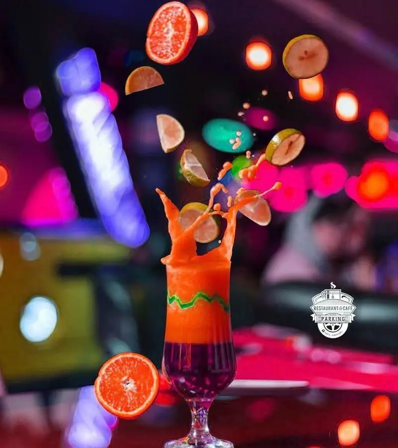صحنه‌ای پویا از نوشیدنی‌های تازه و میوه‌ای در کافی شاپ پارکینگ، تجربه‌ای بی‌نظیر از طعم و رنگ در فضایی مدرن.