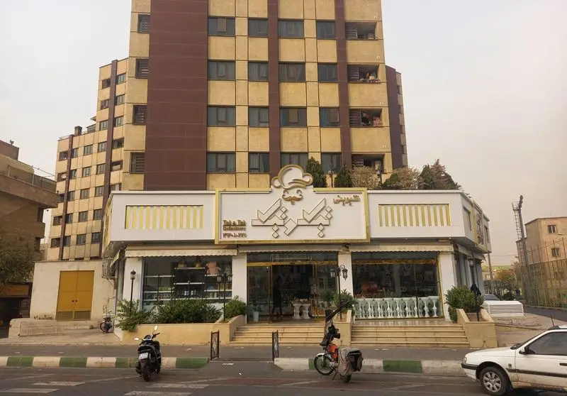 تصویری از نمای خارجی قنادی تیک و تیک در تهران، یک شیرینی فروشی شیک با تابلو برجسته و دکوراسیون زیبا برای انواع کیک و شیرینی.