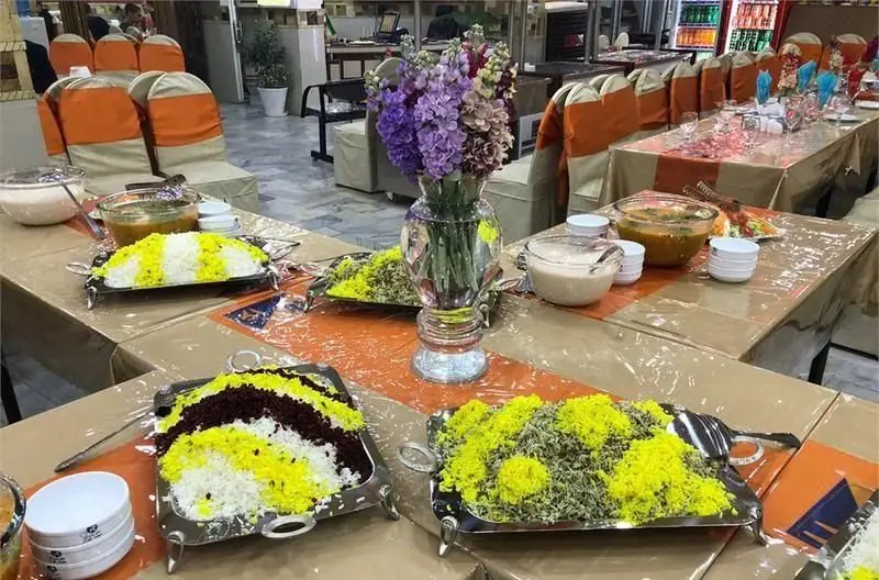 رستوران ایرانی نمونه تهران: میز بوفه مجلل با پلوهای سنتی ایرانی شامل زرشک پلو، شوید پلو و چلو زعفرانی برای مراسمات.