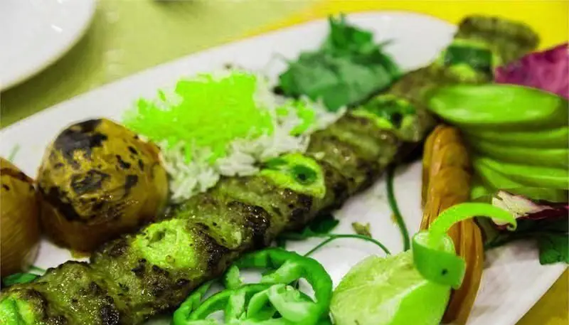 کباب سبز با برنج و گوجه کبابی، به همراه سبزیجات تازه، یک غذای اصیل و لذیذ در رستوران ایرانی نمونه تهران.