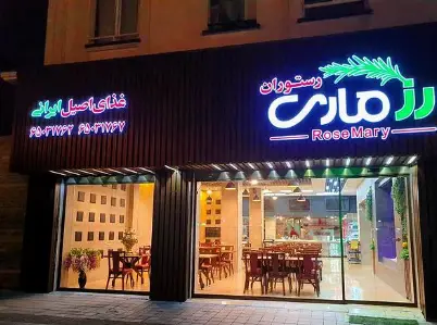 رستوران رزماری (RoseMary)، نمای بیرونی شبانه با تابلوهای نئون روشن، ارائه دهنده غذای اصیل ایرانی، شماره تماس ۶۵۰۲۷۳۶۲