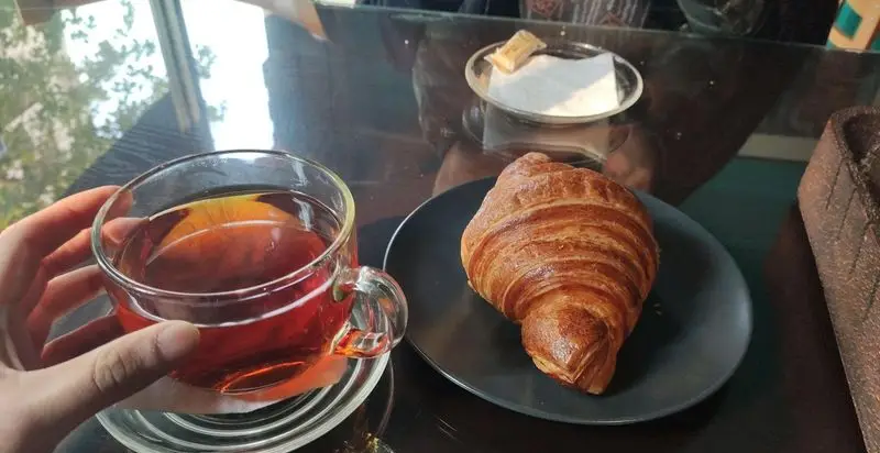 خانه رایا: لذت یک فنجان چای گرم و یک کروسان فرانسوی تازه و خوشمزه. ایده‌آل برای صبحانه یا عصرانه در کافه‌ای دنج.