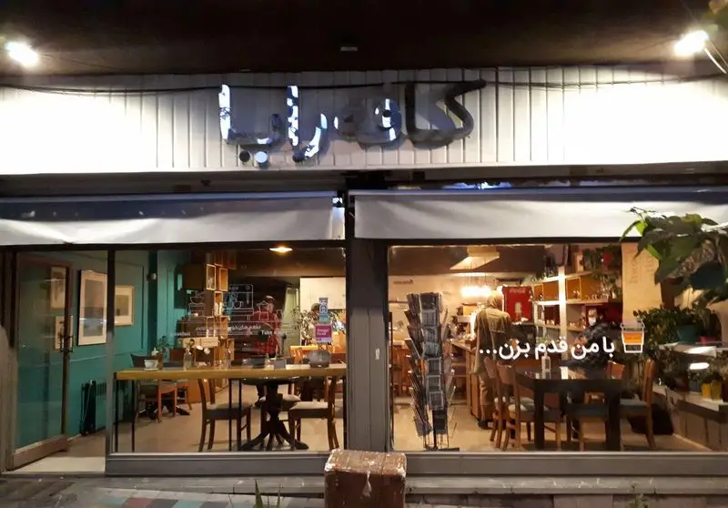 تصویر شبانه کافه و رستوران "خانه رایا" با دکوراسیون داخلی دنج و مدرن، نورپردازی گرم و مشتریان مشغول گفتگو در فضای دوستانه.