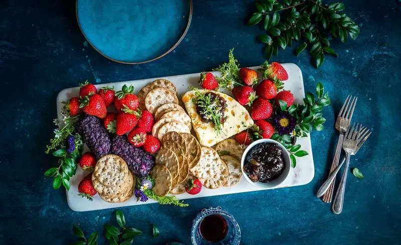 اردوخوری جذاب با توت فرنگی، پنیر و کراکر، نشان دهنده تنوع منو و کیفیت بالای کباب سرای تنور اقدسیه در پذیرایی.