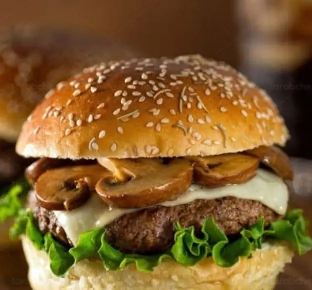 همبرگر قارچ و پنیر بسیار خوشمزه از فست فود هات برگر، با نان کنجدی طلایی، کاهو ترد و قارچ‌های طعم‌دار.