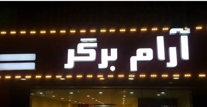 تصویر تابلوی درخشان و برجسته کسب و کار "آرام برگر" در شب، با نورپردازی زیبا، نشان‌دهنده یک رستوران فست فود تخصصی برگر.