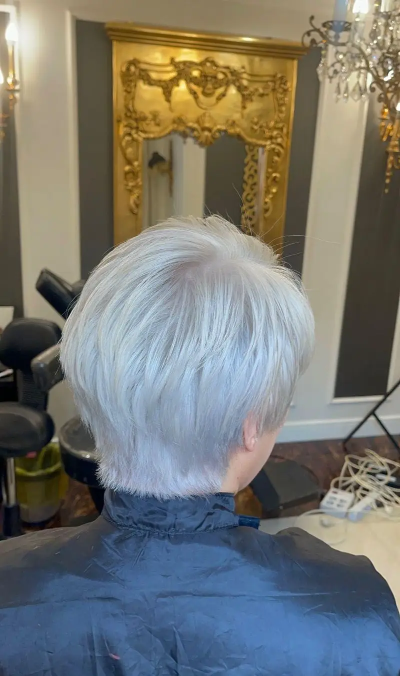 طراحی و اجرای مدل کوتاهی موی زنانه پیکسی با رنگ موی سفید نقره‌ای و دکلره کامل از نمای پشت سر در سالن زیبایی موزا