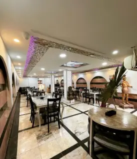 فضای داخلی شیک و مدرن رستوران خانسالار با میز و صندلی‌های مرتب و نورپردازی بنفش، محیطی آرامش‌بخش برای مشتریان.