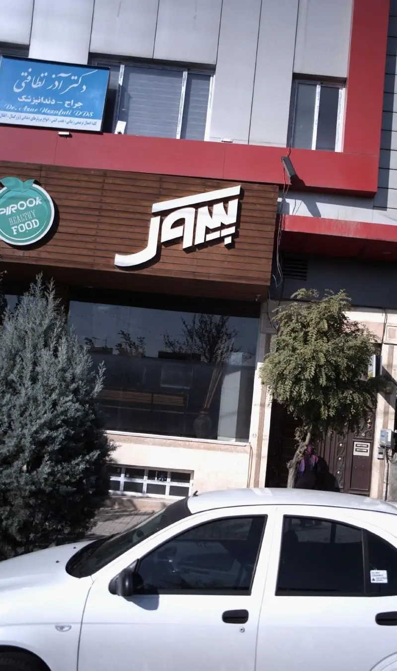 نمای بیرونی رستوران پیتزا پیروک، با تابلوی بزرگ «پیروک غذای سالم» و یک خودروی سفید پارک شده در جلو.