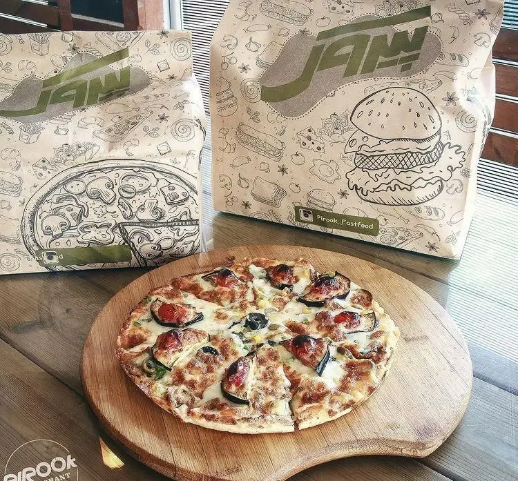 پیتزا مخصوص پیروک با پنیر، بادمجان و زیتون در کنار کیسه های فست فود جذاب رستوران پیروک برای سفارش آنلاین و بیرون بر.