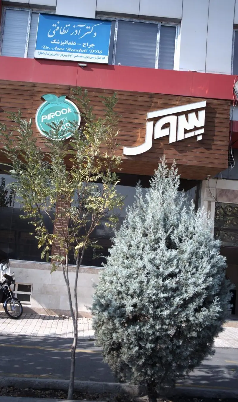 تصویری از نمای خارجی رستوران پیتزا پیروک با تابلوی سبز رنگ Pirook Healthy Food و نام بزرگ Pirook روی نمای چوبی، در کنار فضای سبز و درختان.