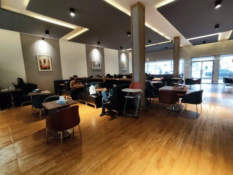 فضای داخلی مدرن و دنج کافه رستوران ویسلند با دکوراسیون شیک، میز و صندلی راحت و کفپوش چوبی روشن.