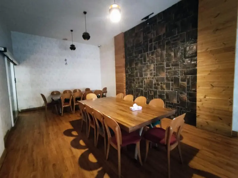 فضای داخلی کافه رستوران ویسلند با میزهای چوبی بزرگ و کوچک، صندلی‌های شیک، کفپوش چوبی و دیوار سنگی. محیطی مدرن و دنج برای مشتریان.