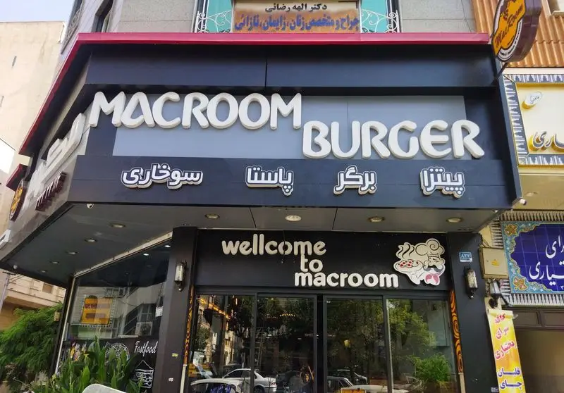 نمای کامل بیرونی فست فود و رستوران پیتزا مکروم با سردر جذاب، نمایشگر لوگوی Macroom Burger و غذاهایی مانند پیتزا، برگر، پاستا و سوخاری