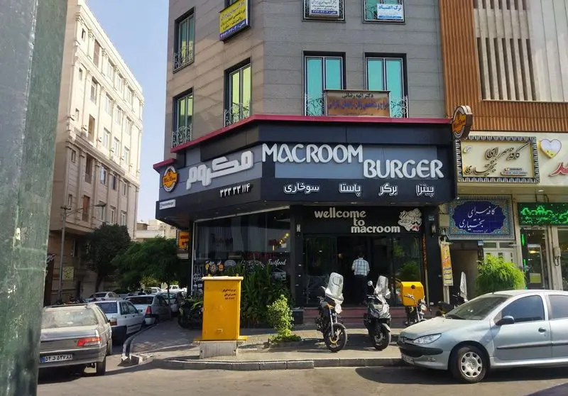 نمای بیرونی فست فود پیتزا مکروم، رستورانی معروف برای برگر، پیتزا و پاستا، با تابلوی Macroom Burger در خیابان شلوغ شهر.