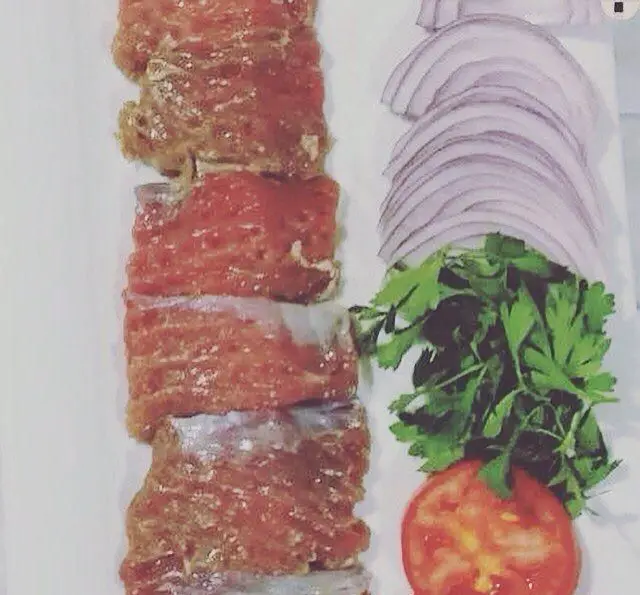 رستوران ایرانی شاندیز ماهان: آماده‌سازی مواد اولیه کباب شامل گوشت تازه، پیاز، جعفری و گوجه فرنگی برای غذای اصیل ایرانی.