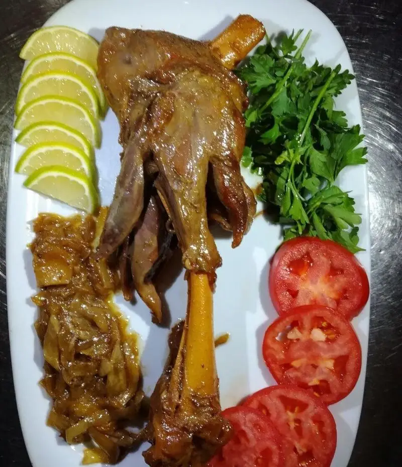 خوراک ماهیچه گوسفندی لذیذ در رستوران ایرانی شاندیز ماهان؛ همراه با پیاز داغ، لیمو، سبزی و گوجه فرنگی. غذای سنتی اصیل.